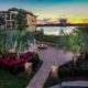 Luxury outdoor living design in Orlando by BLG Environmental, featuring layered palms, tropical plantings, a paver patio, and a lakeside fire pit at sunset.