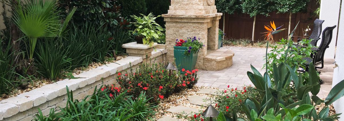 Backyard design for an Orlando estate home featuring a structured patio layout, stone fire feature, and layered landscape planting