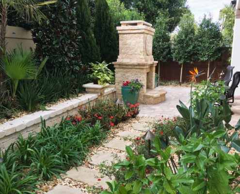 Backyard design for an Orlando estate home featuring a structured patio layout, stone fire feature, and layered landscape planting